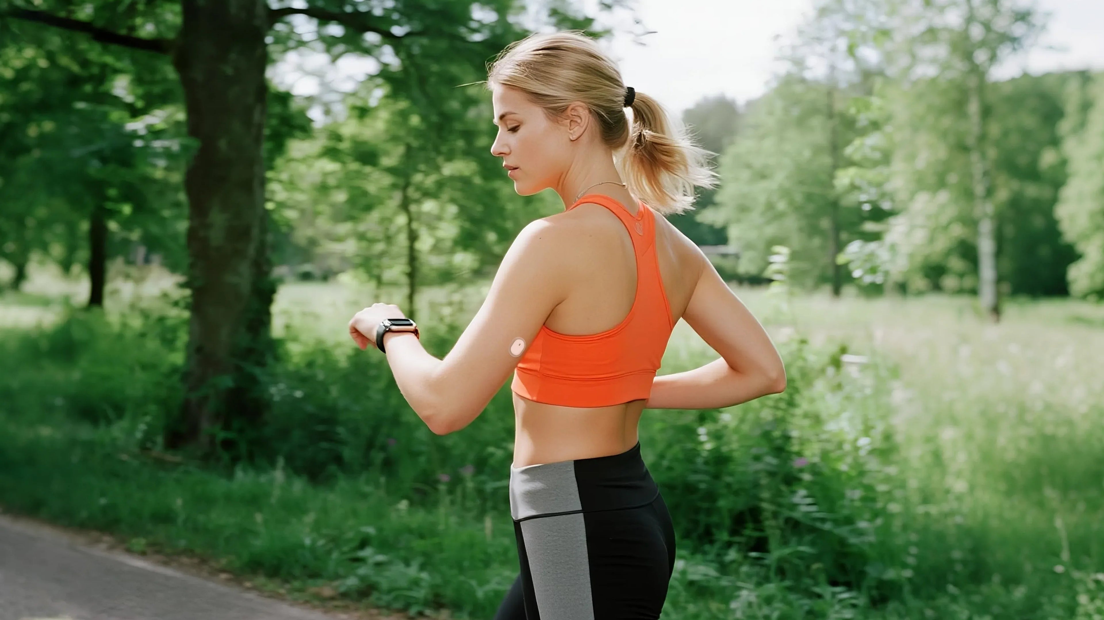 Woman in orange sports bra checks smartwatch outdoors. Glucose monitor patch on arm. Keywords: Sibionics, glucose monitor, outdoor activity.